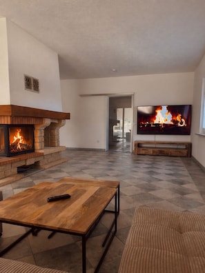 Ein Wohnzimmer mit Kamin, Fernseher und einer Couch.