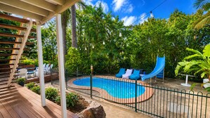 A pool with a slide, wooden deck, and lounge chairs. - Spacious Family Retreat with Pool, Waterslide & Dual Living Minutes from Beaches (Kuluin)