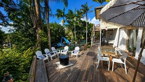 A wooden deck with white chairs, a table, and a slide. - Spacious Family Retreat with Pool, Waterslide & Dual Living Minutes from Beaches (Kuluin)