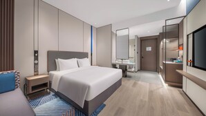 Una habitación de hotel moderna con una cama grande, un escritorio, un espejo y un televisor.