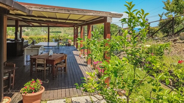 A covered outdoor patio with a table and chairs, surrounded by potted plants and a view of the countryside. - Tra Cielo e Mare - Rooms Rio Marina - Tra Cielo e Mare - Curcuma (Rio Marina)