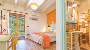 A bedroom with a bed, a window, and a bathroom with a sink and mirror. - Tra Cielo e Mare - Rooms Rio Marina - Tra Cielo e Mare - Curcuma (Rio Marina)