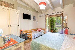 A room with a bed, a desk with a kettle, a TV, and a window with a view of greenery. - Tra Cielo e Mare - Rooms Rio Marina - Tra Cielo e Mare – Paprika (Rio Marina)