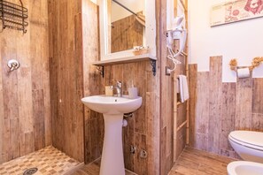 Ein Badezimmer mit Holzvertäfelung, Waschbecken, Spiegel, Dusche und Toilette.