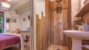 Una stanza con un letto, una doccia con pareti in legno, un lavandino e una finestra vista.