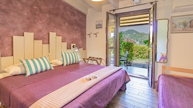Una camera da letto con un letto, una sedia e vista su un giardino e montagne.