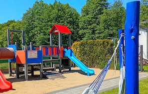 Ein Spielplatz mit einer roten Rutsche, einer blauen Rutsche und einer Kletterkonstruktion.