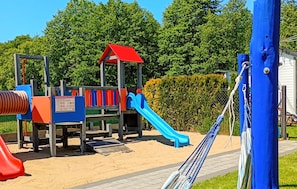 Ein Spielplatz mit einer roten Rutsche, einer blauen Rutsche und einer Kletteranlage.