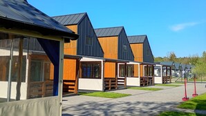 A row of modern cabins with large windows, a flat roof, and a paved walkway. - 2 bedroom lovely home in Rusinowo (Rusinowo)
