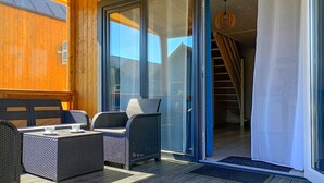 A covered outdoor seating area with wicker furniture, a glass door leading to a staircase, and a wooden wall. - 2 bedroom lovely home in Rusinowo (Rusinowo)