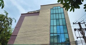 A building with a large glass window, a flat roof, and visible power lines. - Classic Adithya Stay (Hyderabad)