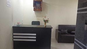 Ein Empfangstresen mit Blumenvase, ein gerahmtes Bild darüber und eine Couch im Hintergrund.