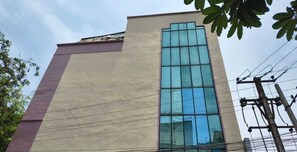 A building with a large glass window and a beige facade. - Classic Adithya Stay (Hyderabad)