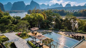A resort with a swimming pool, lounge area, and views of a river and mountains. - Wushan Chujian Homestay (Guilin)