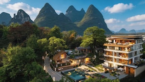 Un resort con piscina, edificios de varios pisos y montañas al fondo.
