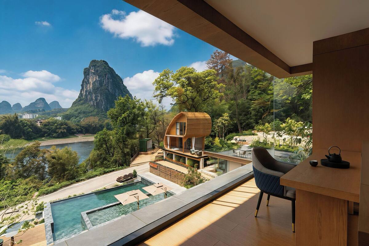 Una casa moderna con piscina, terraza de madera y vista a la montaña y al río.