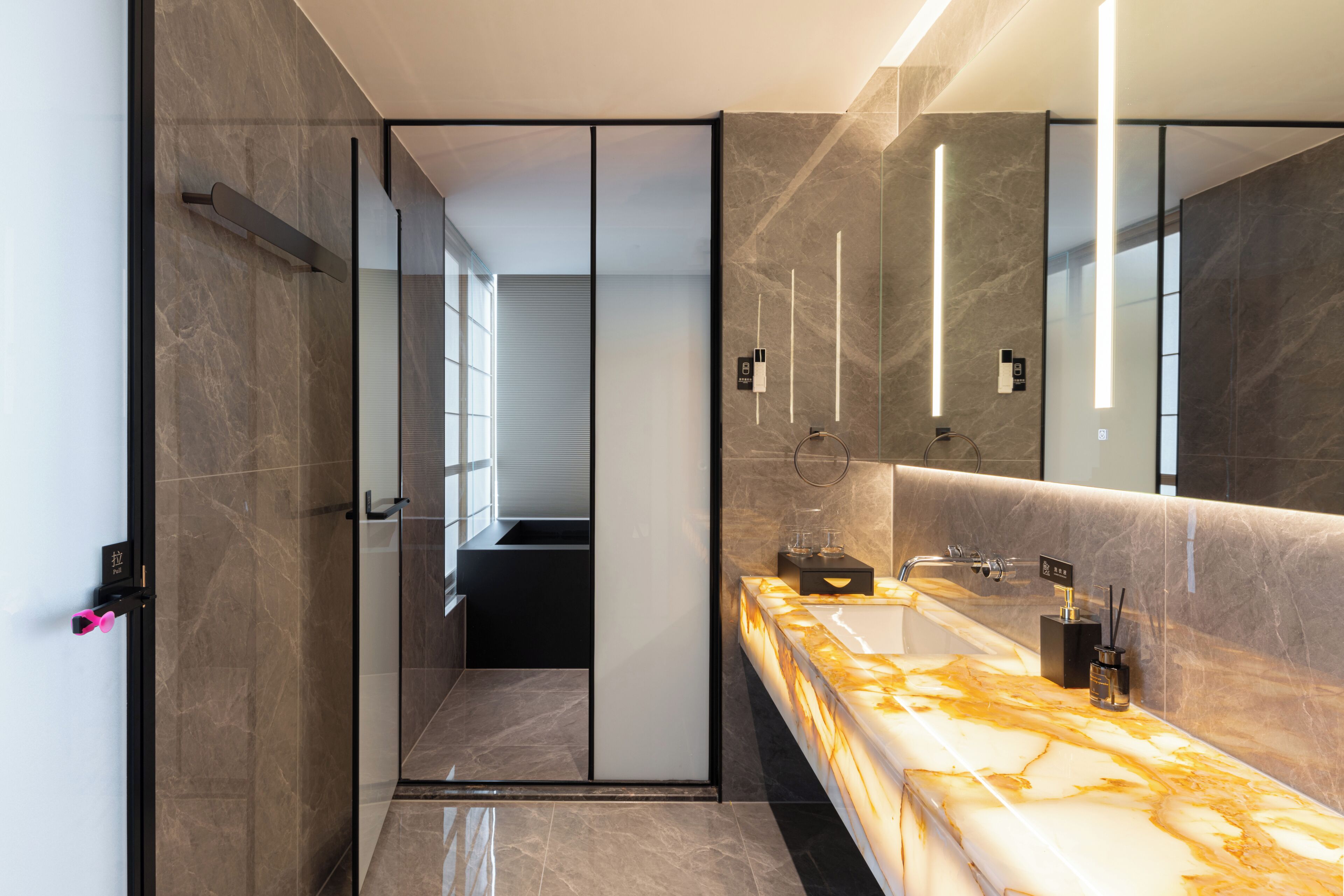 Une salle de bain moderne avec un meuble-lavabo en marbre, un grand miroir et une douche à parois de verre.