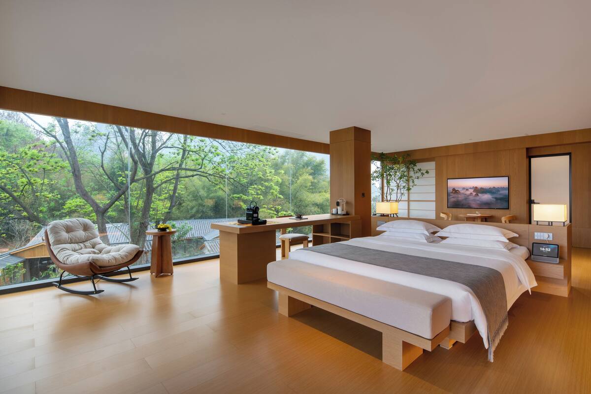 Un dormitorio moderno con una cama grande, una mecedora, un escritorio y un televisor.