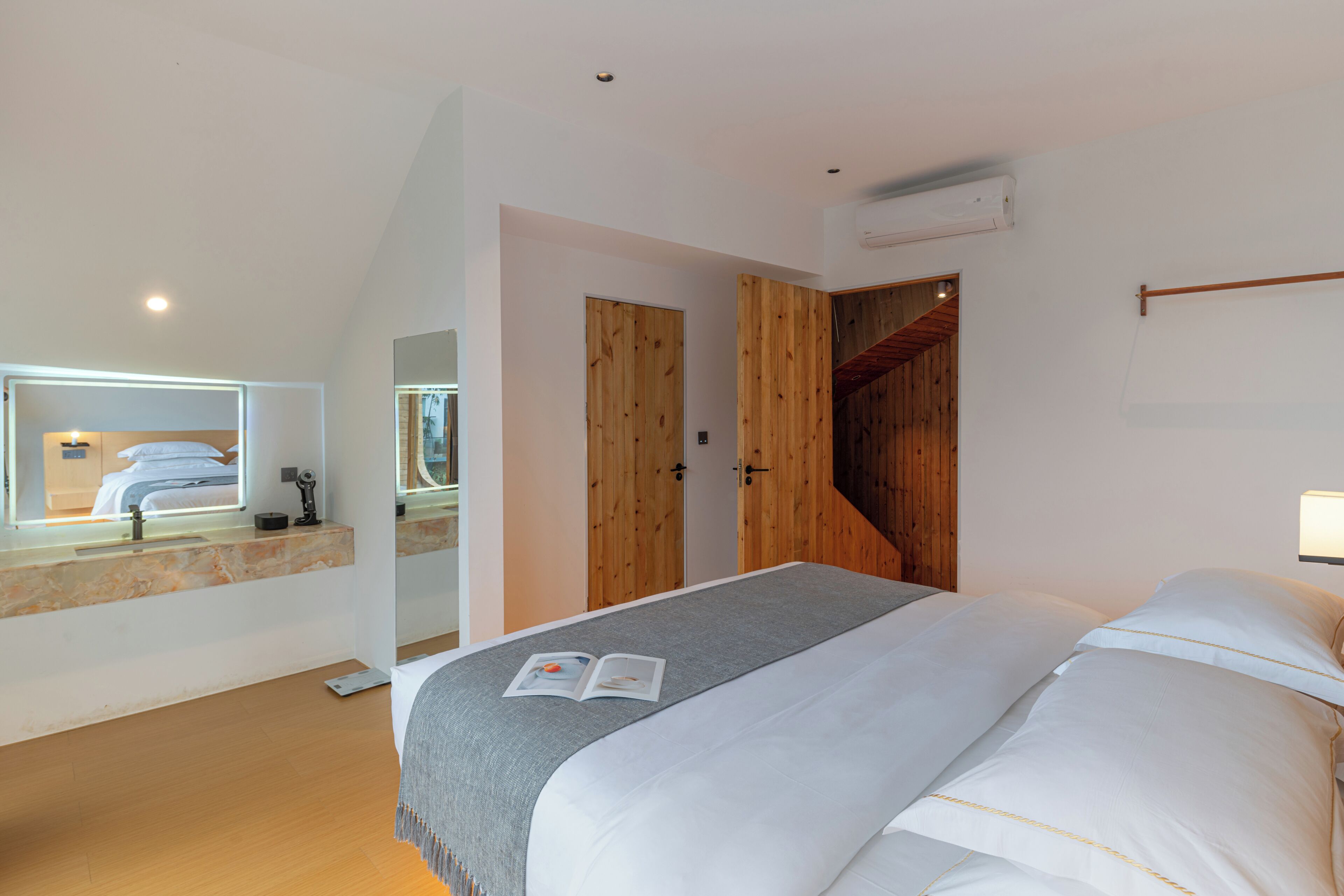 Un dormitorio con cama, una puerta de madera, un espejo y una ventana.