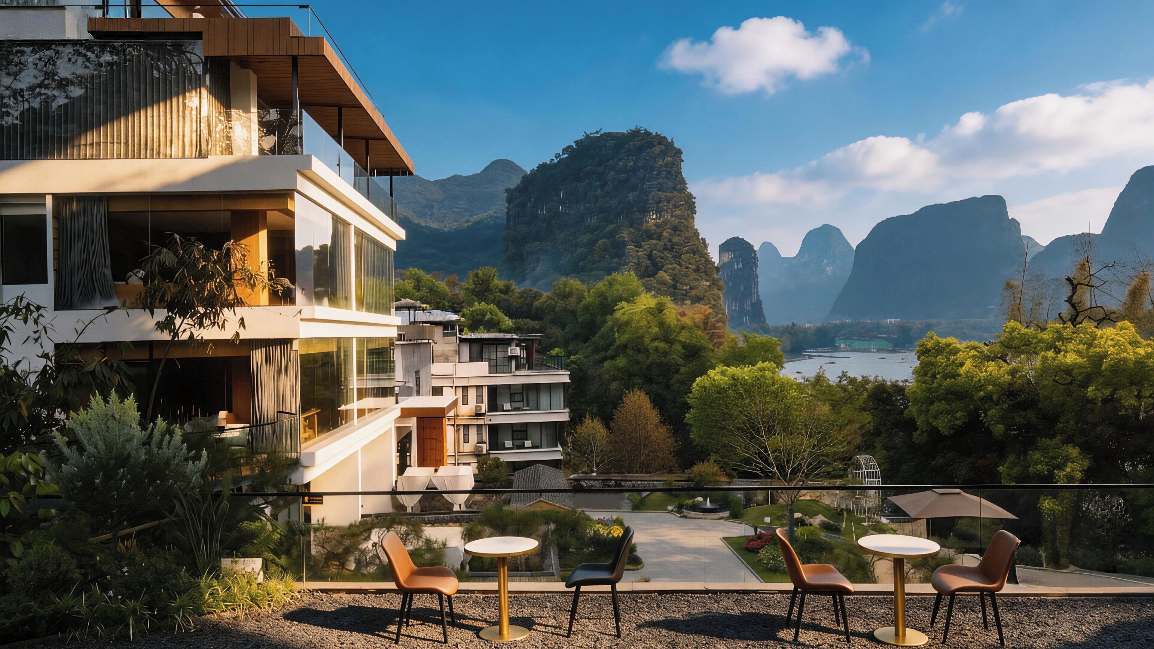 Un hotel moderno con terraza y vistas a un paisaje montañoso y una masa de agua.