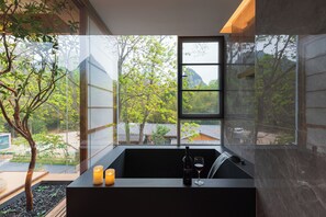 A modern bathroom with a large window, a black sink, and two candles. - Wushan Chujian Homestay (Guilin)