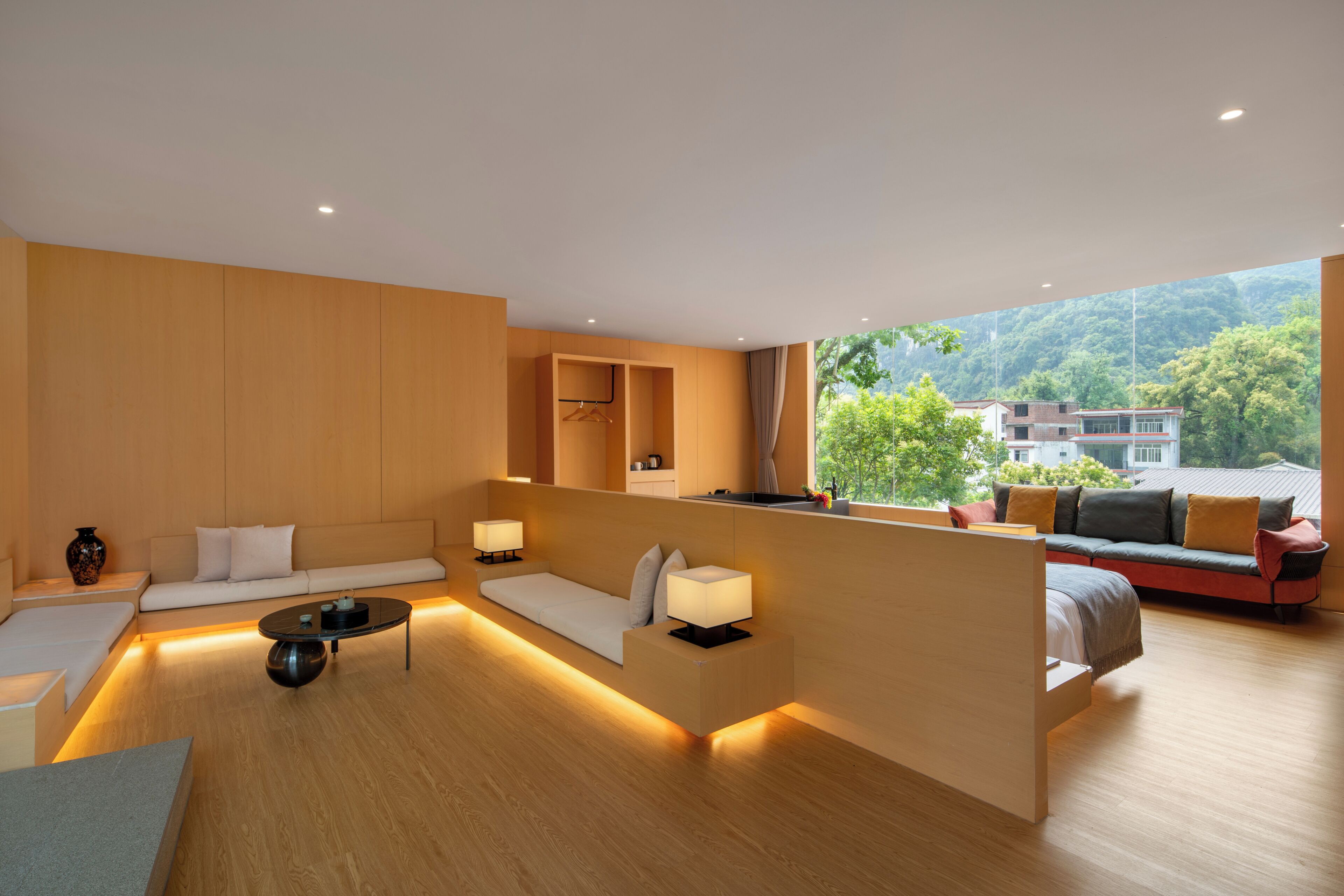 A modern living room with a sofa, a coffee table, and a view of a green landscape.