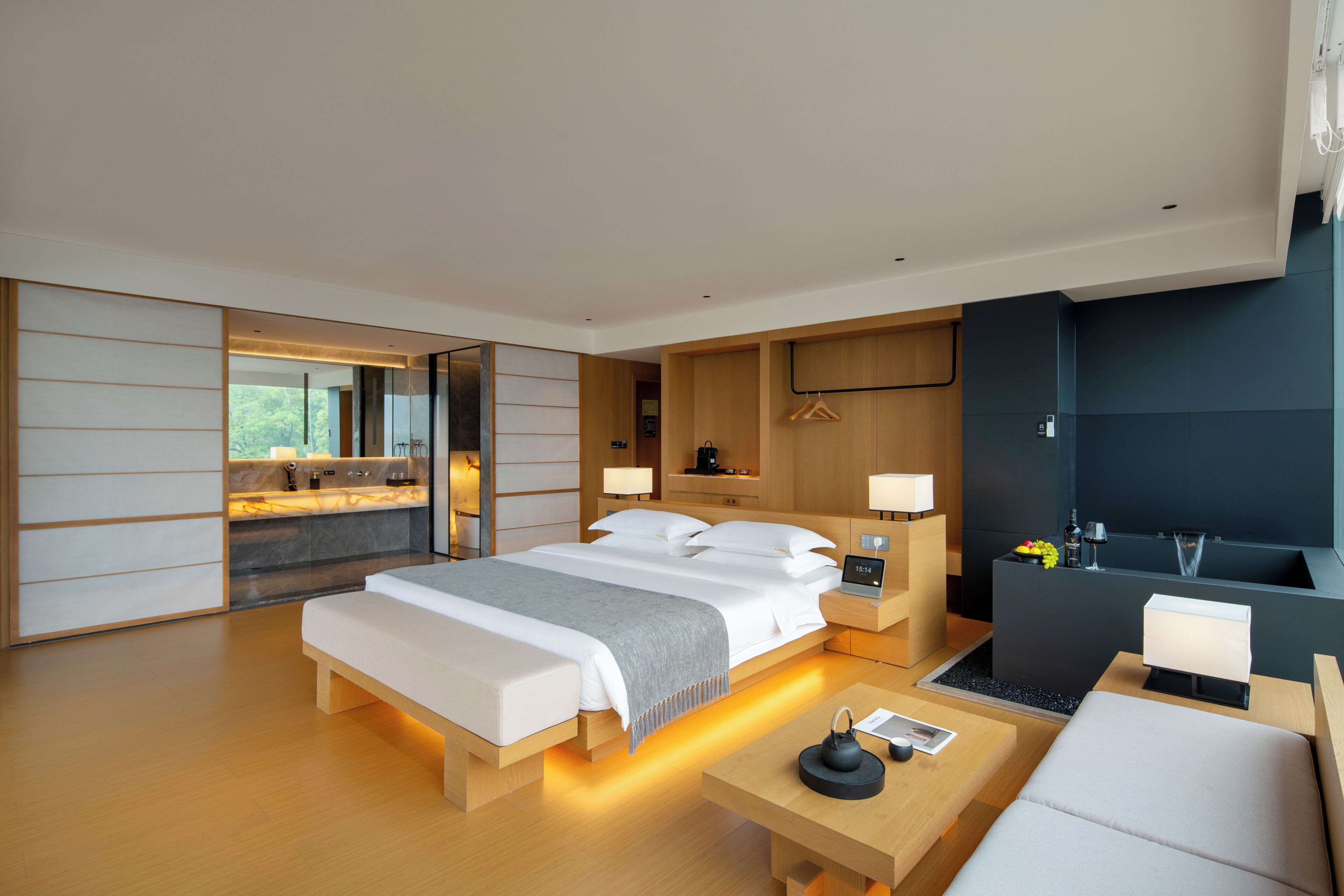 A modern hotel room with a large bed, bedside tables, a desk, and a seating area.