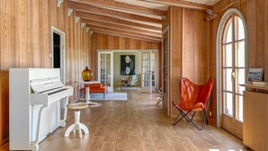 A spacious room with wooden paneling, a piano, a red chair, and a large window. - 3 bedroom stunning home in Varberg (Varberg)