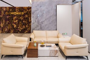A modern living area with a beige sofa set, a marble coffee table, and a decorative wall with the text 'DEMORES'. - Verse Manor Hotel Shanghai (Shanghai)