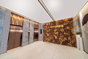 A modern elevator area with two elevators, a floral wall, and a clean, tiled floor. - Verse Manor Hotel Shanghai (Shanghai)