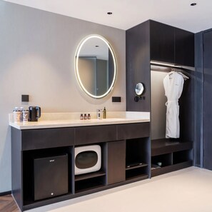 A modern bathroom with a vanity, a round mirror with lighting, a robe hanging, and a small cabinet. - Verse Manor Hotel Shanghai (Shanghai)