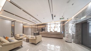 Un vestíbulo moderno con mostrador de recepción, zona de estar y un robot aspirador.