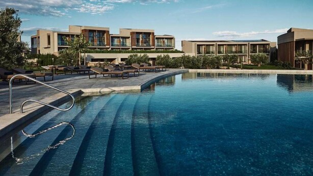 Ein modernes Hotel mit Pool, Liegestühlen und blauem Himmel.