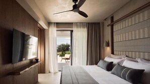 Ein Schlafzimmer mit Bett, Deckenventilator, Fernseher und Blick ins Freie.