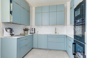 Eine moderne Küche mit hellblauen Schränken, einer weißen Arbeitsplatte und einem eingebauten Backofen.