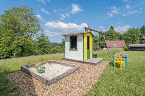 A play area with a sandbox, a small shed, and a yellow chair. - Hideaway Lodge Trtinka (Zalec)