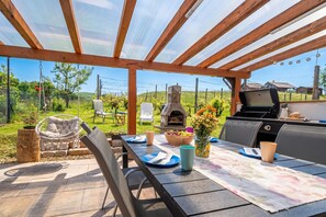 An outdoor patio with a grill, seating, and a view of the countryside. - Hideaway Lodge Trtinka (Zalec)