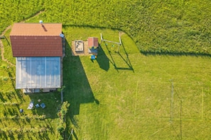 A large glass greenhouse structure with a red roof, surrounded by a grassy field. - Lodge Trtinka /w Terrace & BBQ in Nature (Zalec)