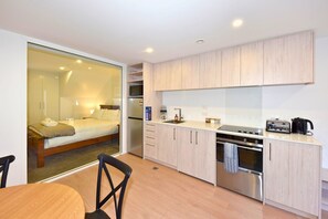 A compact hotel room with a bed, kitchenette, and a sliding door leading to a balcony. - Stylish 1BR Stay on Moorhouse Avenue (Christchurch)