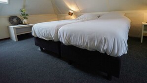 Un dormitorio con cama, mesitas de noche, una lámpara y un pequeño objeto decorativo en la mesita.