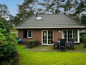 A house with a tiled roof, brick walls, and a patio with outdoor furniture. - Villa in Beekbergen With Terrace (Beekbergen)