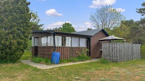 Une cabane en bois avec une cour clôturée, une porte bleue et un petit porche.