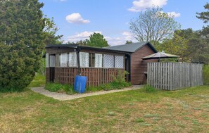 A wooden cabin with a fenced yard, a blue door, and a small porch. - Awesome home in Vibble with WiFi (Vibble)