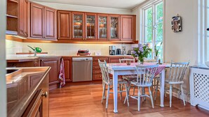 A kitchen with wooden cabinets, a dishwasher, a dining table with chairs, and a window with a view of greenery. - 4 bedroom stunning home in Borghamn (Borghamn)
