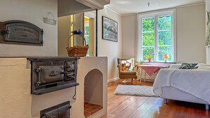 A room with a fireplace, a dining area with a table and chairs, a bed, and a window with a view of trees. - 4 bedroom stunning home in Borghamn (Borghamn)
