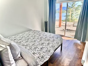 Una camera da letto con un letto, vista all'esterno tramite una porta scorrevole e una finestra con tende.