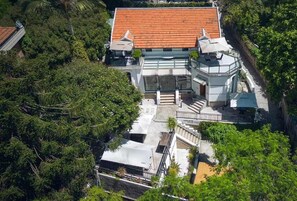 Ein mehrstöckiges Gebäude mit rotem Ziegeldach, einem überdachten Außenbereich mit Sitzgelegenheiten und einer Treppe, die zu einer oberen Ebene führt.