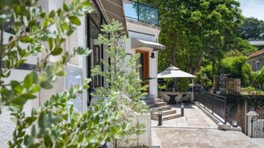 Une maison moderne dotée d’un balcon, d’un espace salon extérieur et d’un jardin.