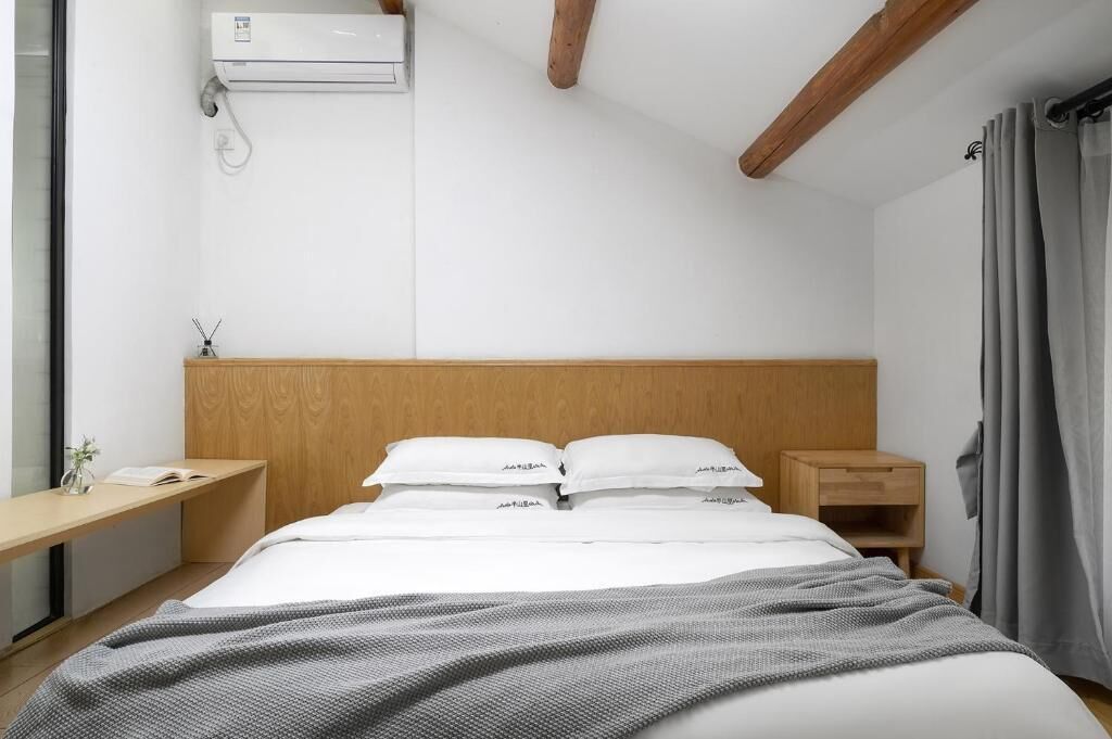 Un dormitorio con cabecera de madera, mesita de noche y cortinas.