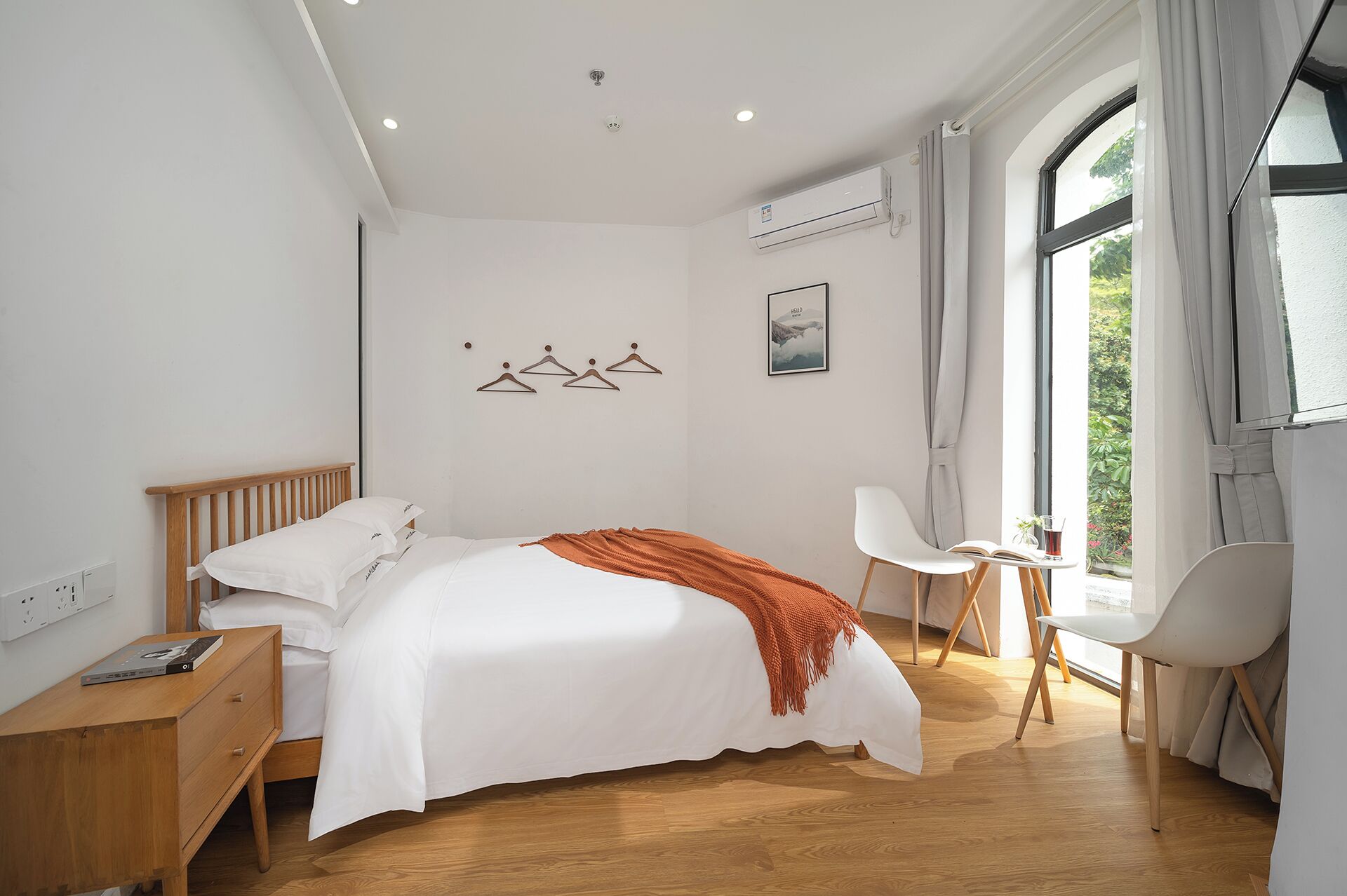 Una camera da letto con un letto, un comodino, una sedia e una finestra con tende.